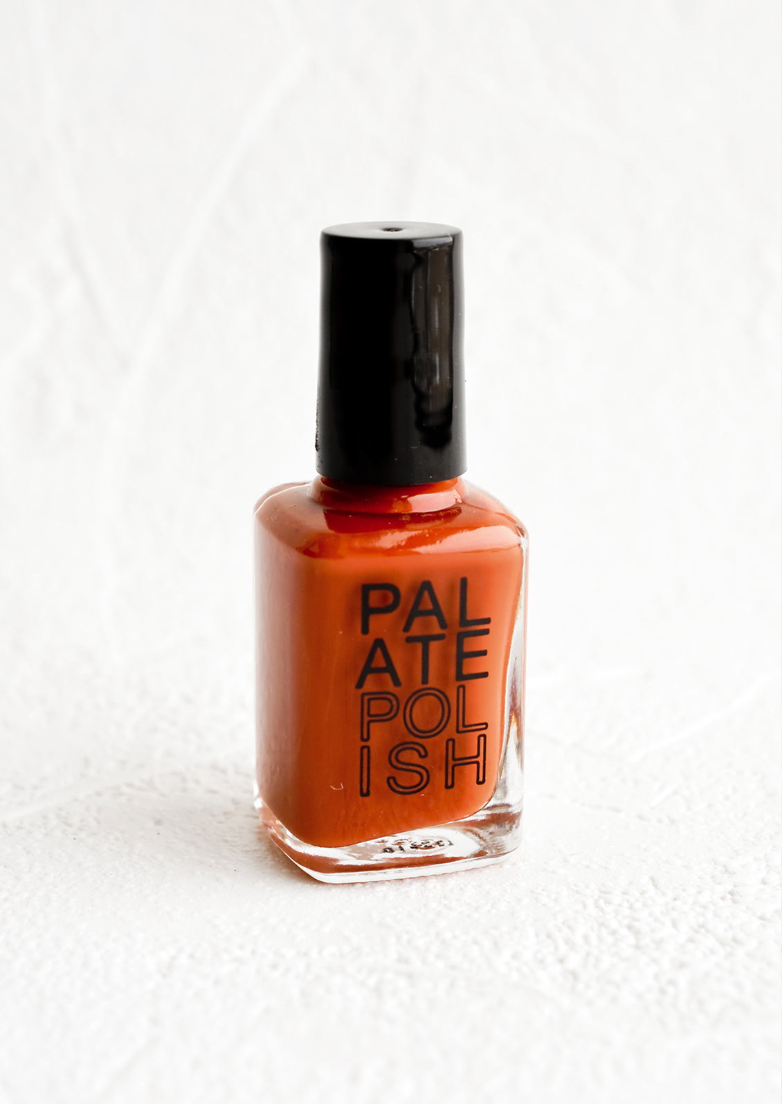A bottle of nail polish in rust red.