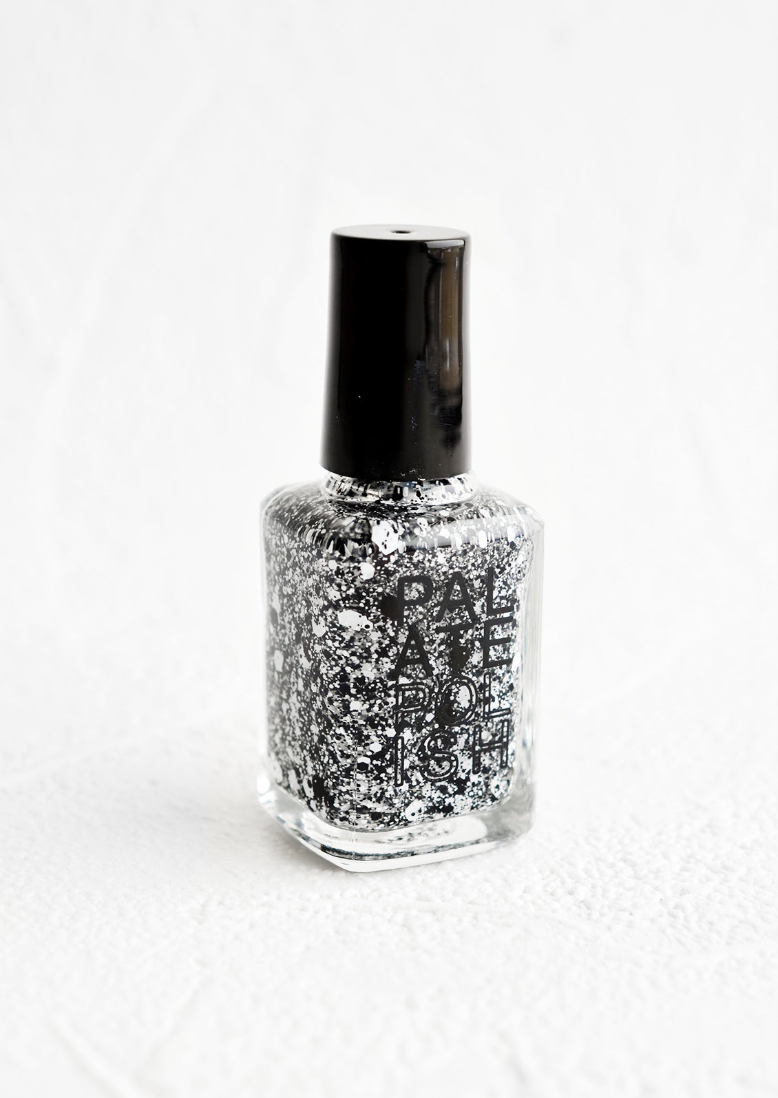A bottle of nail polish in black and white glitter.