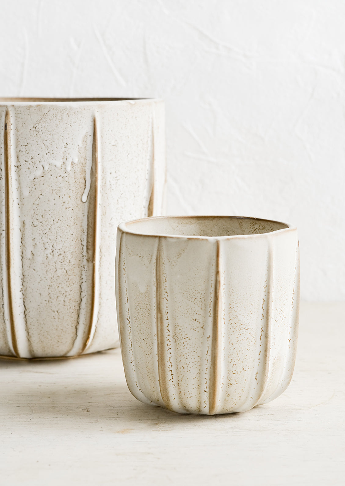Small and large tan ceramic planters.