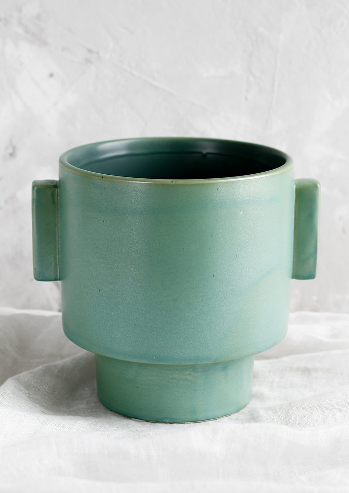 A ceramic planter in turquoise glaze with straight side tabs.