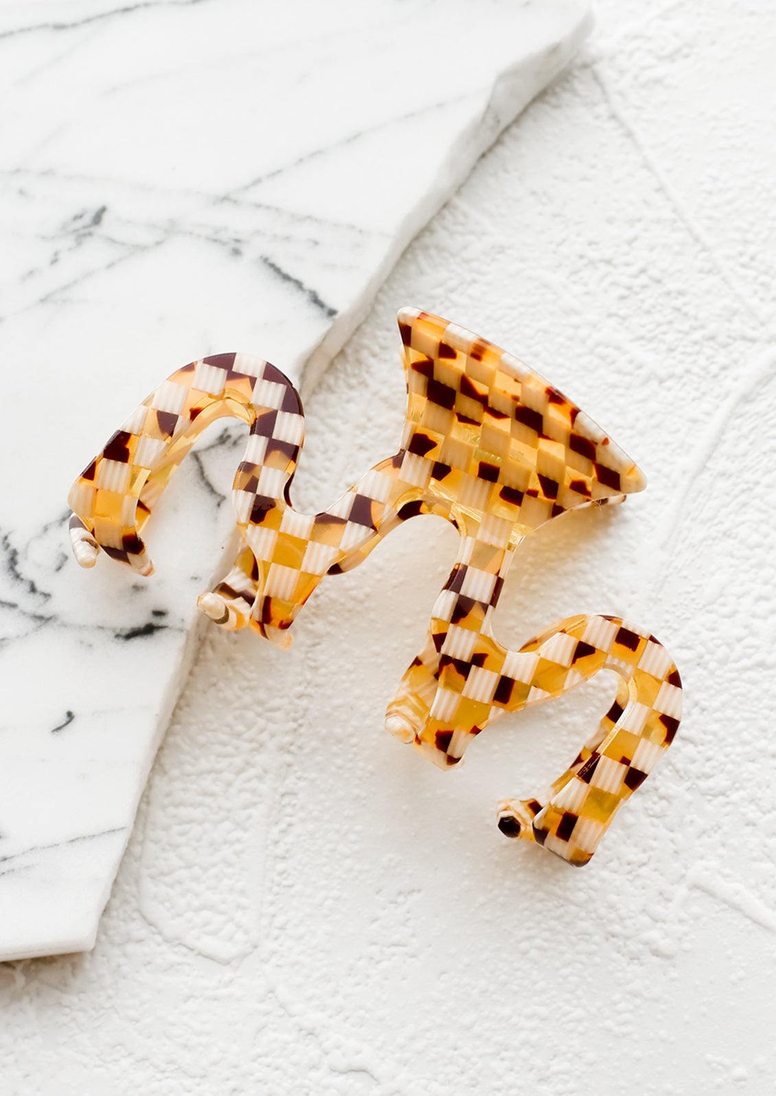 An acetate hair clip in squiggle shape in basketweave print.