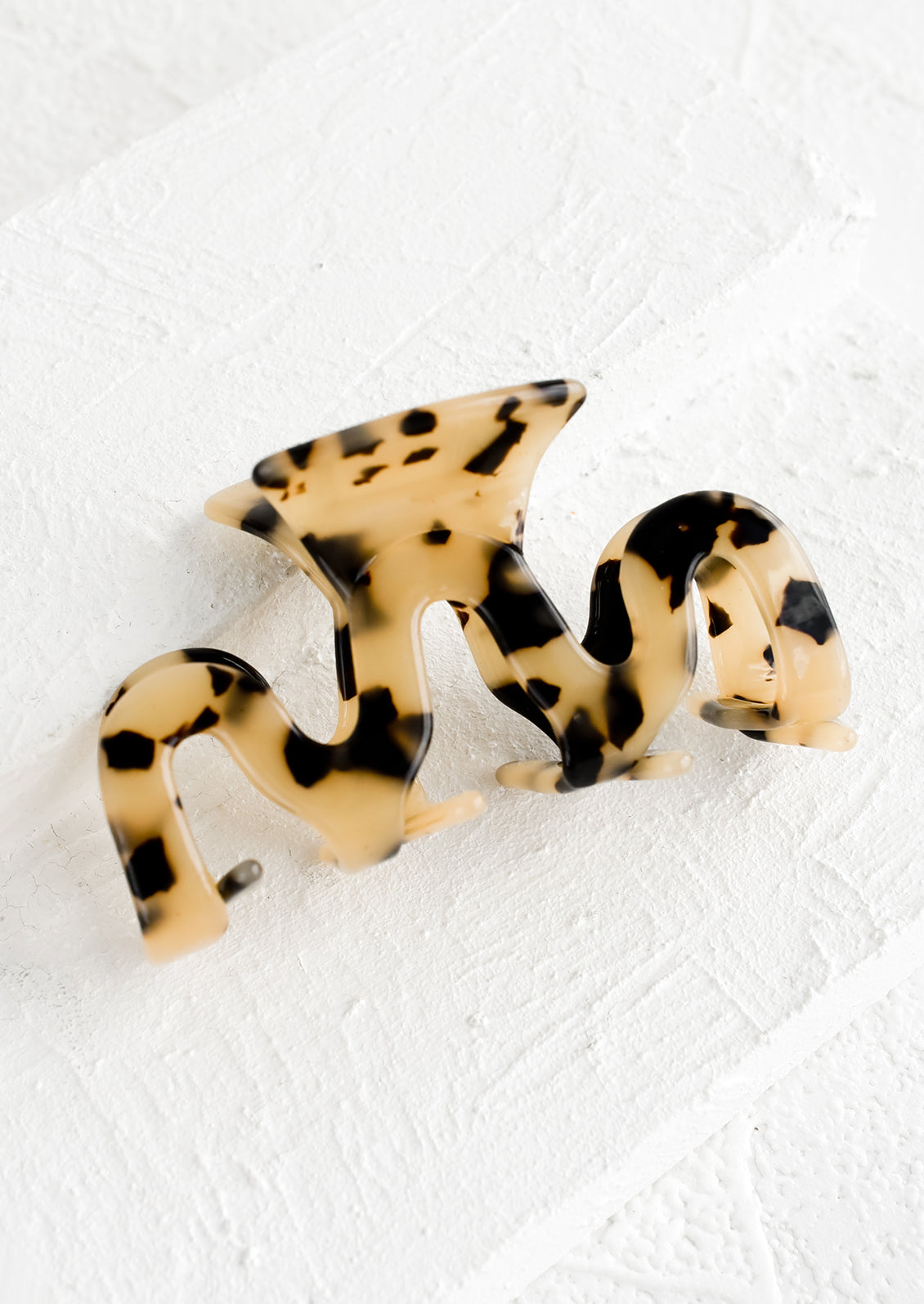 An acetate hair clip in squiggle shape in tortoise print.
