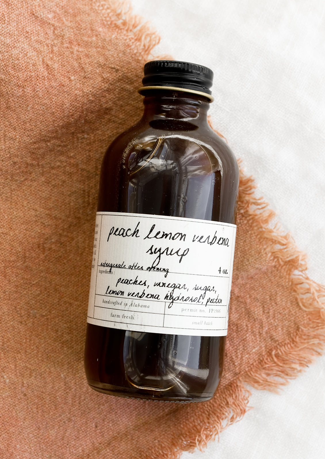 A glass bottle of peach lemon verbena syrup.