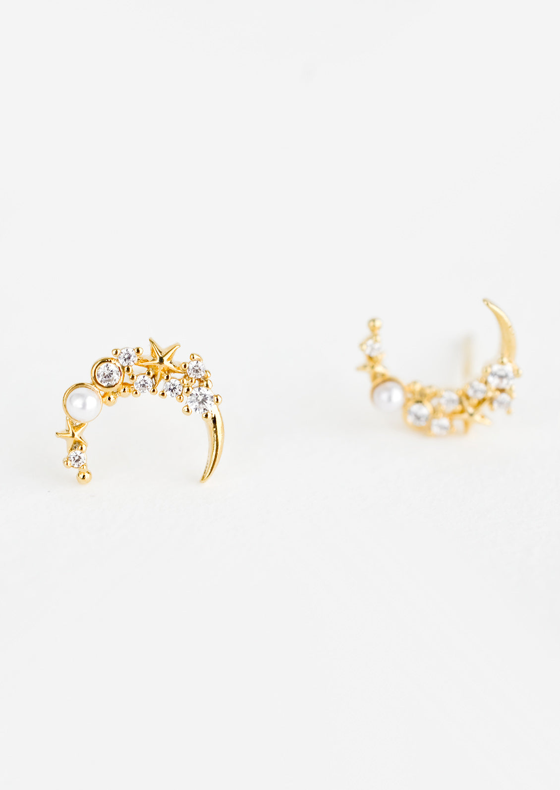 A pair of gold crescent moon shaped earrings with crystal and pearl detailing.