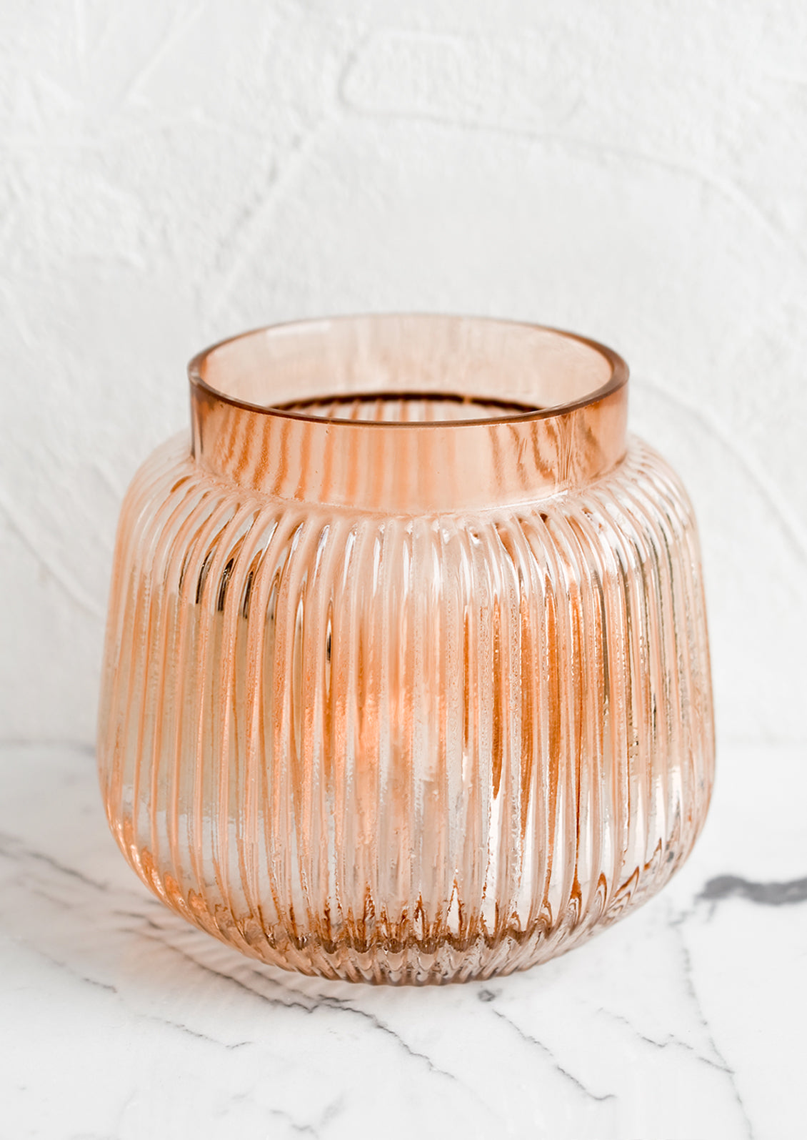 A short glass vase with wide opening and ribbed texture.