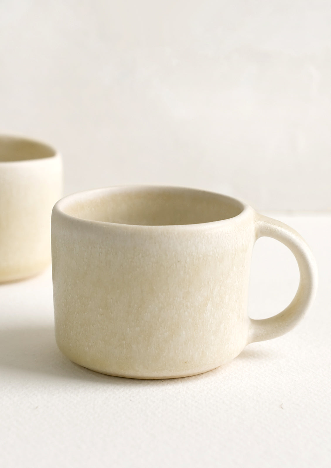A ceramic espresso mug with handle in neutral ivory glaze.