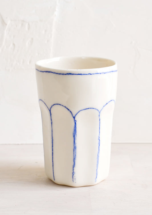 A ceramic tumbler with blue lines.