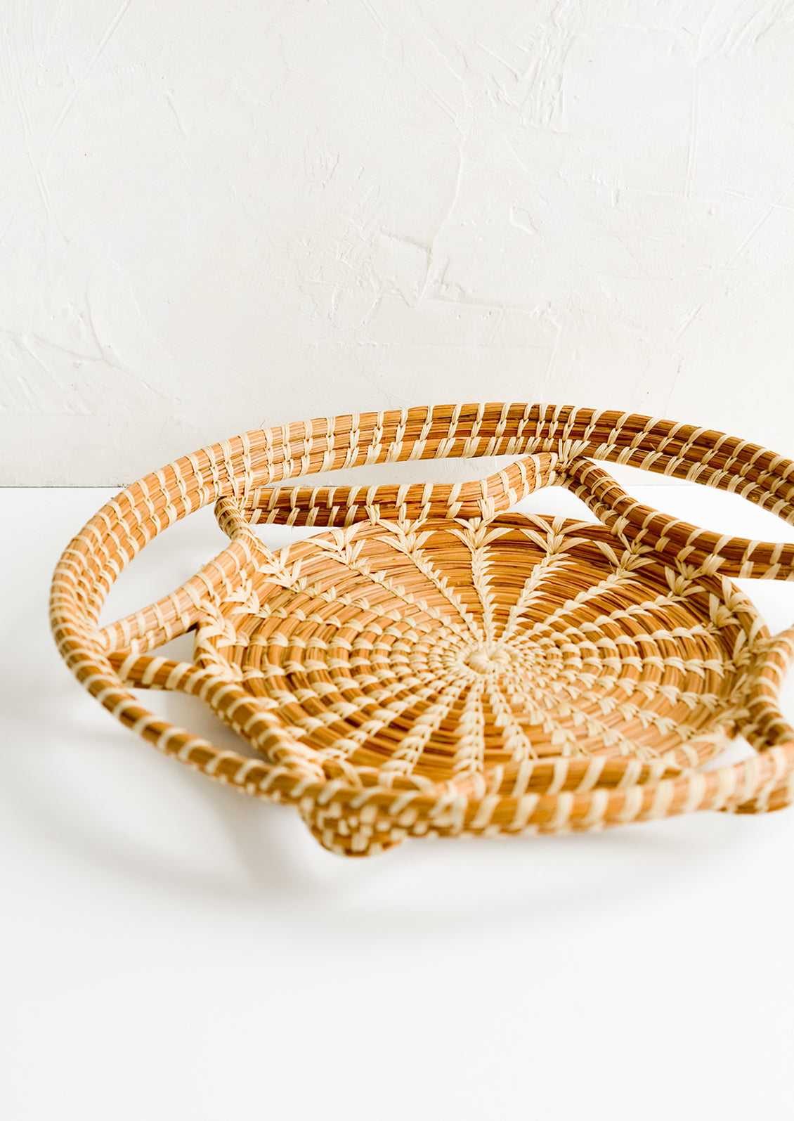 A round, flat tray with curved open weave design.