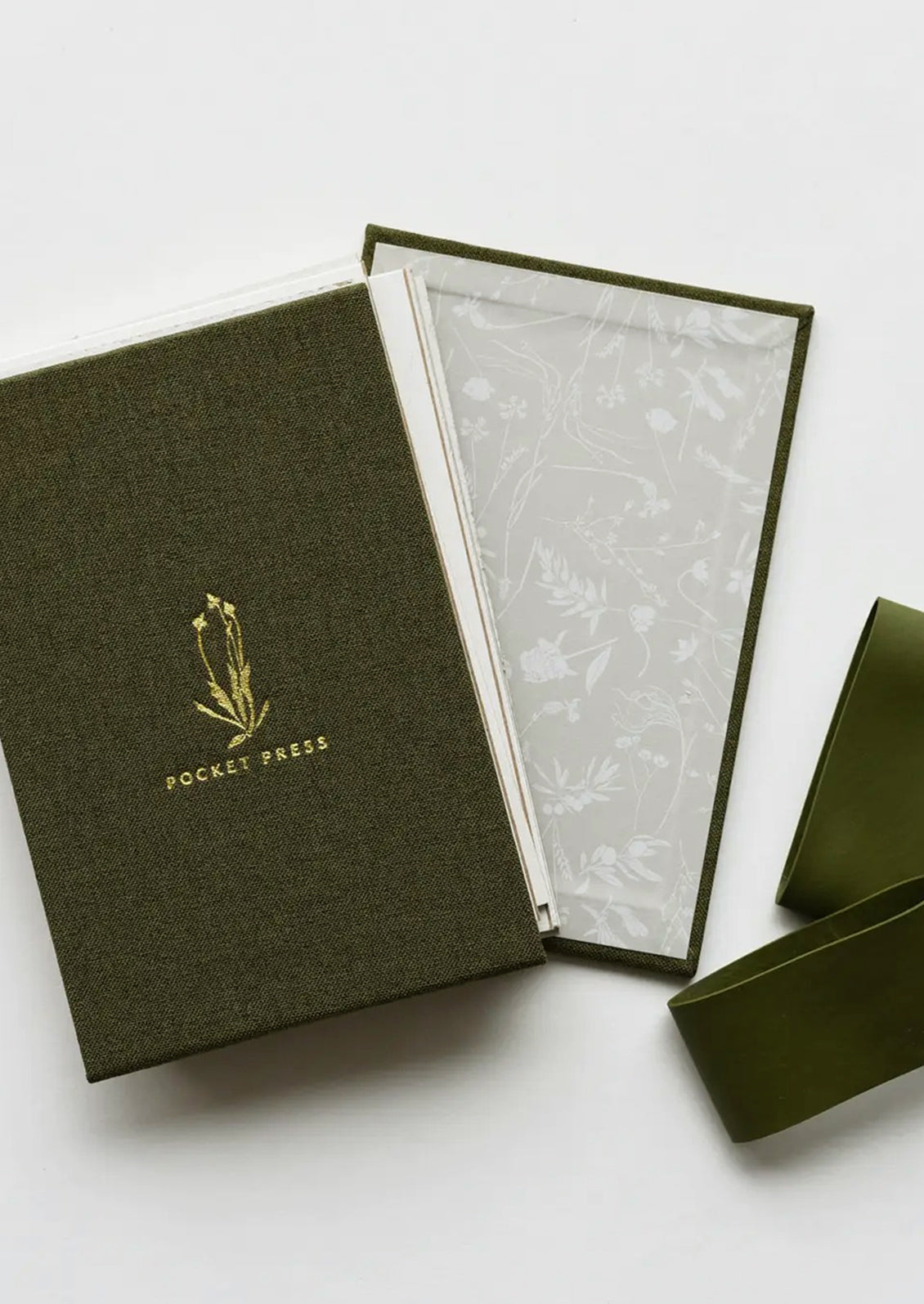 A green linen covered pocket-sized flower press booklet.