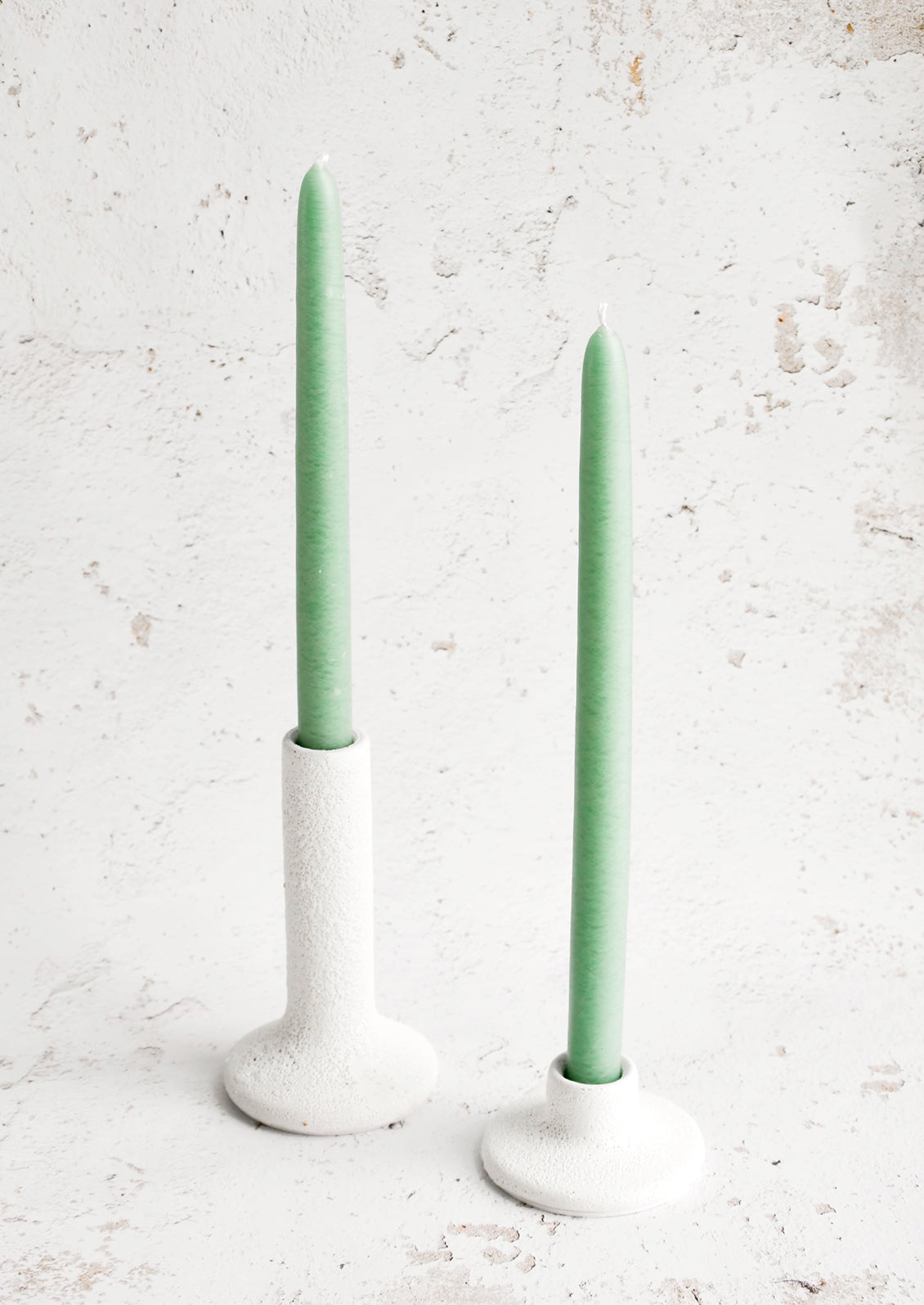 White ceramic taper candle holders in short and tall heights, displaying seafoam green taper candles