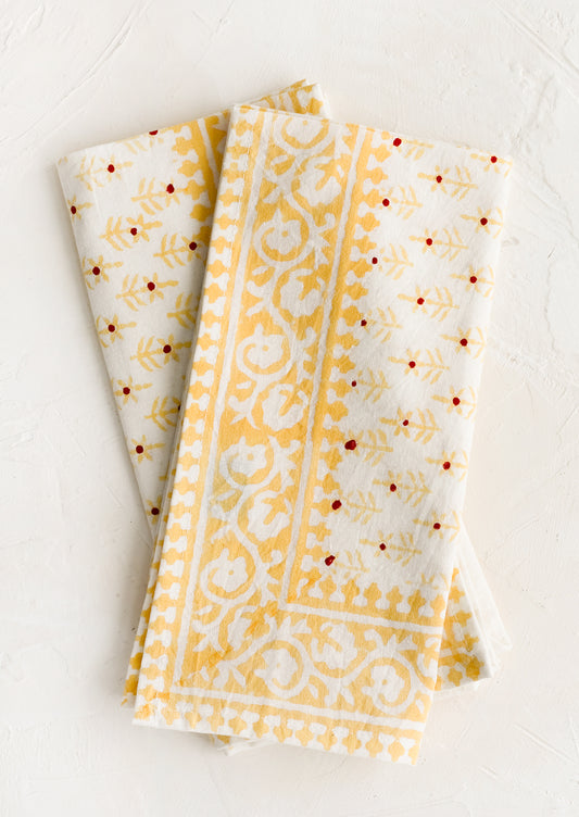 A pair of block printed napkins with yellow and red floral print.