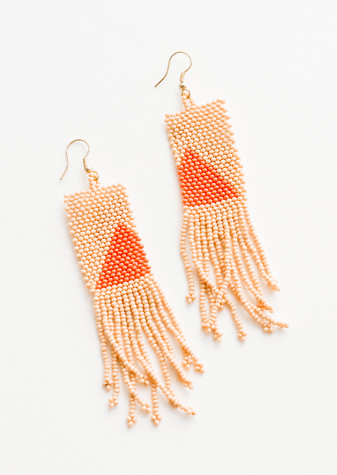 Long rectangular fringe beaded earrings in peach with orange triangle designs.
