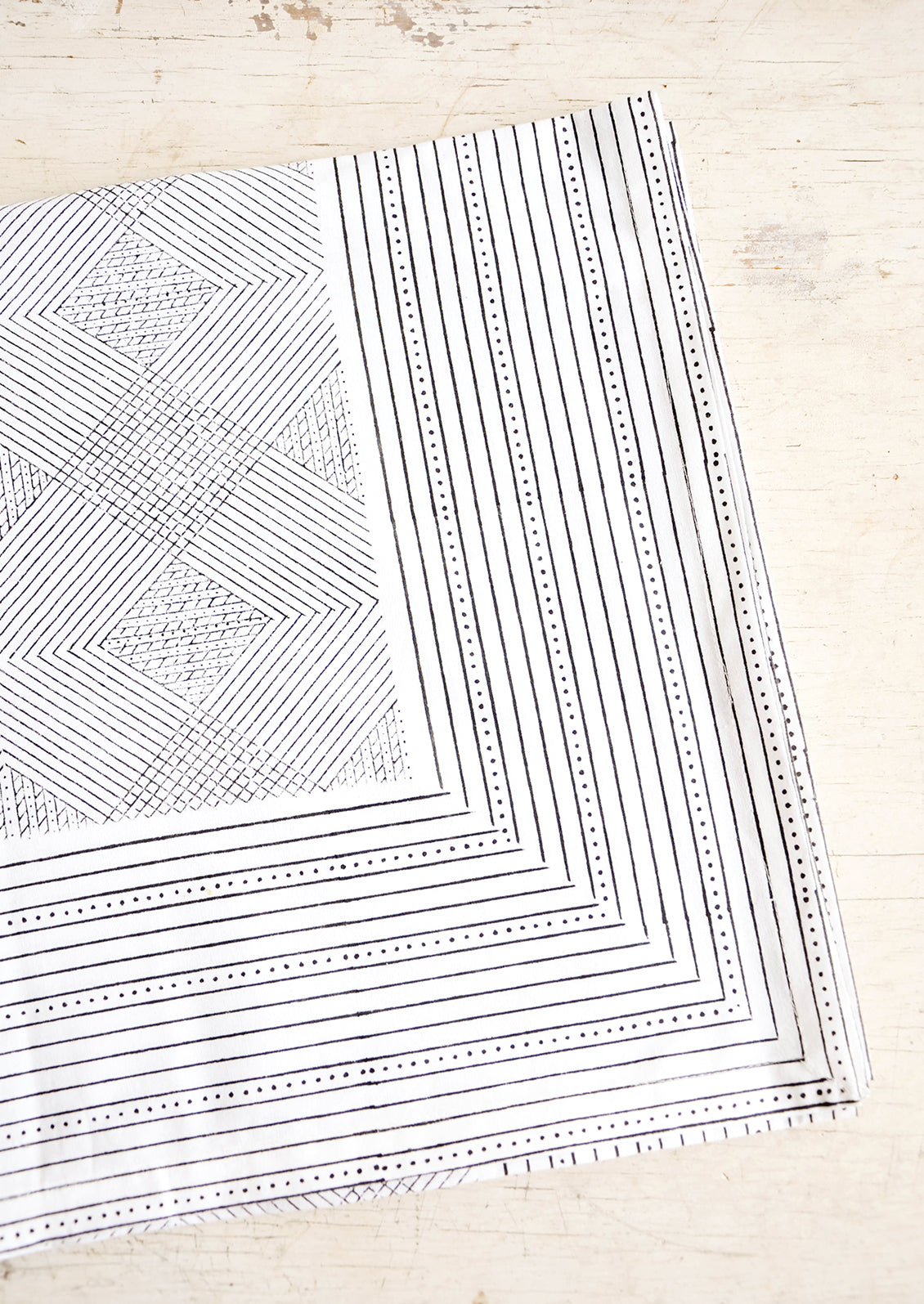 Black and white cotton tablecloth with geometric line and diamond print, displayed folded