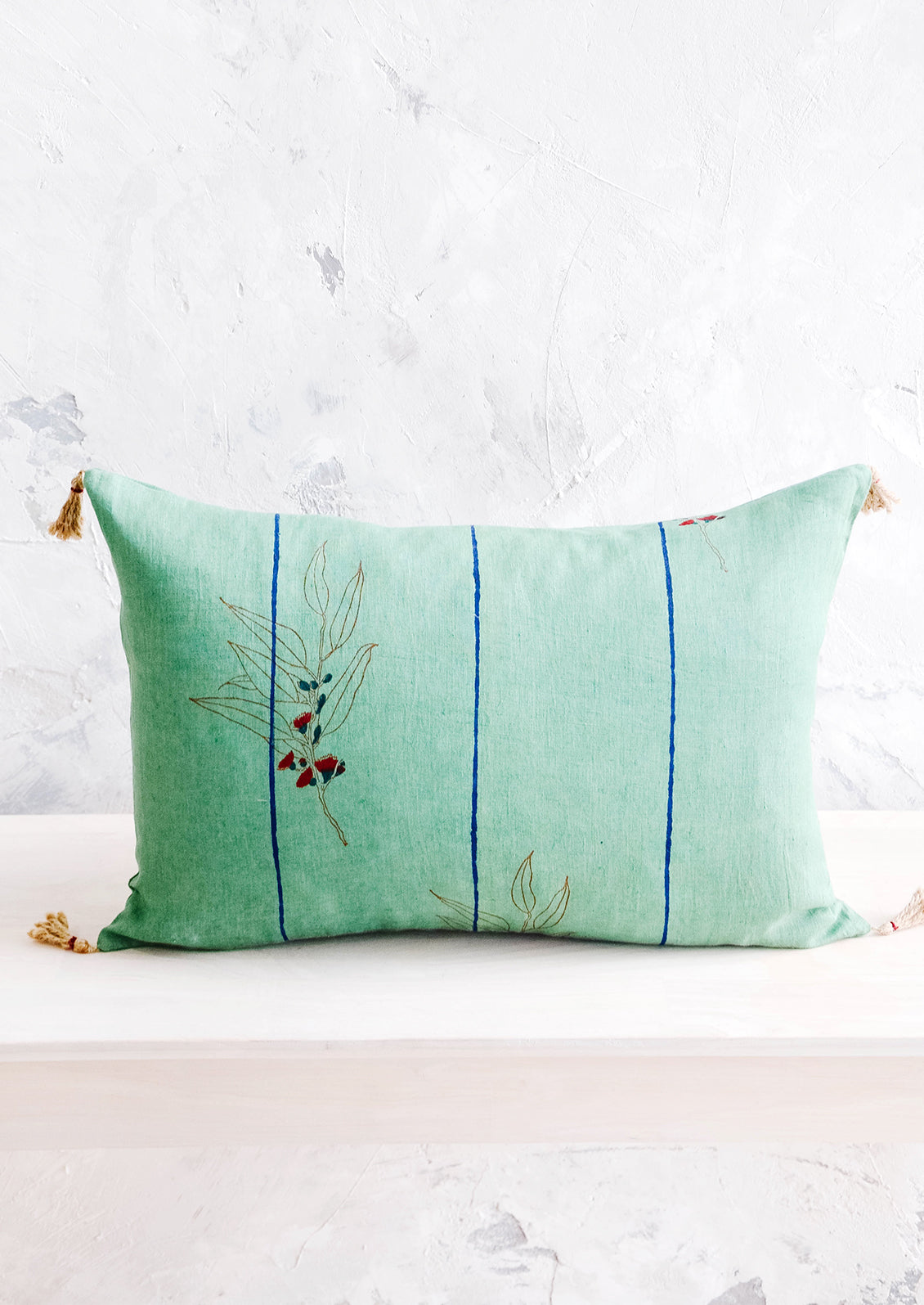 Decorative lumbar throw pillow in jade green linen with blue stripes and block printed floral detail