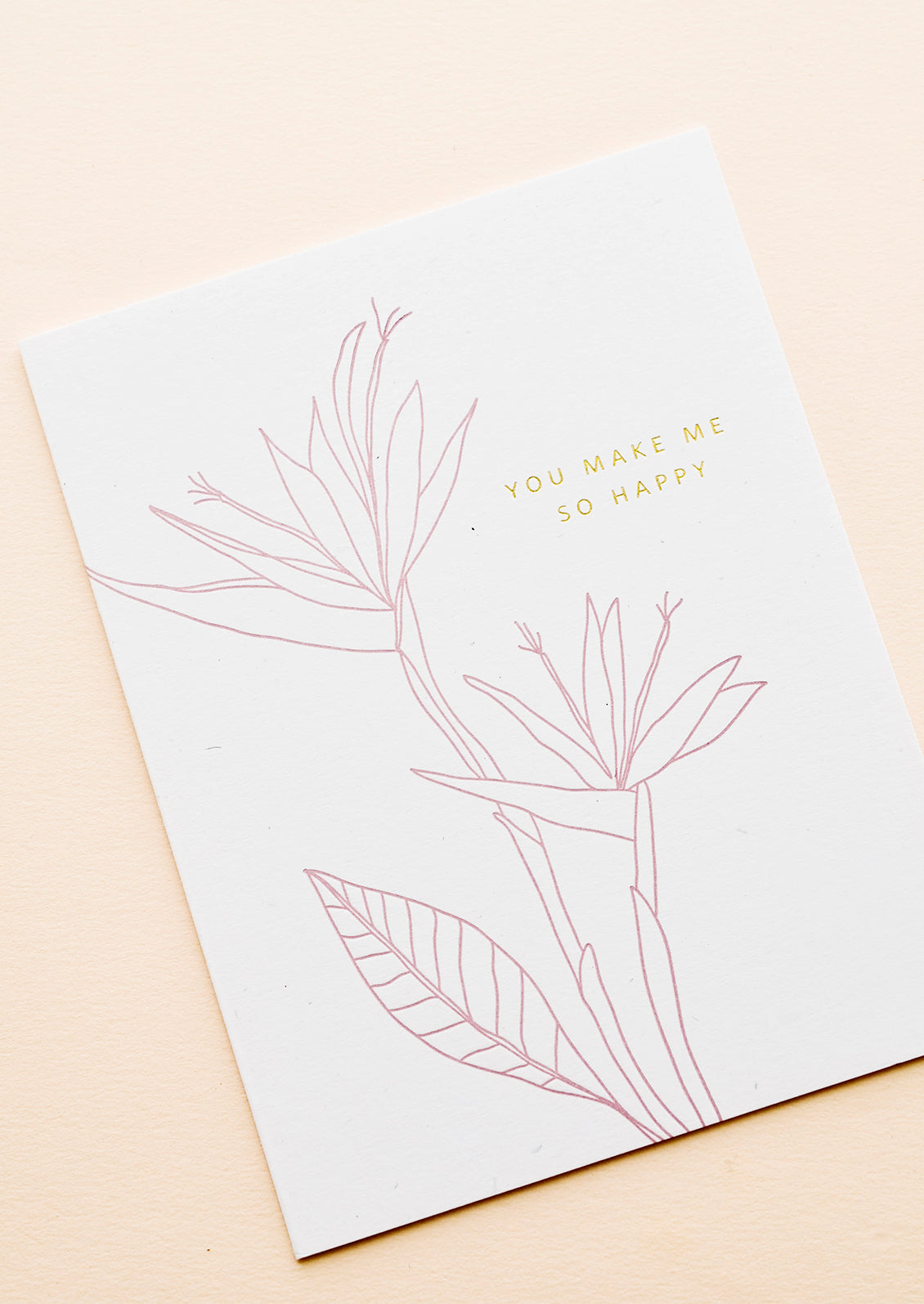 Greeting card with pink flower outline drawing and gold text reading "You make me so happy"