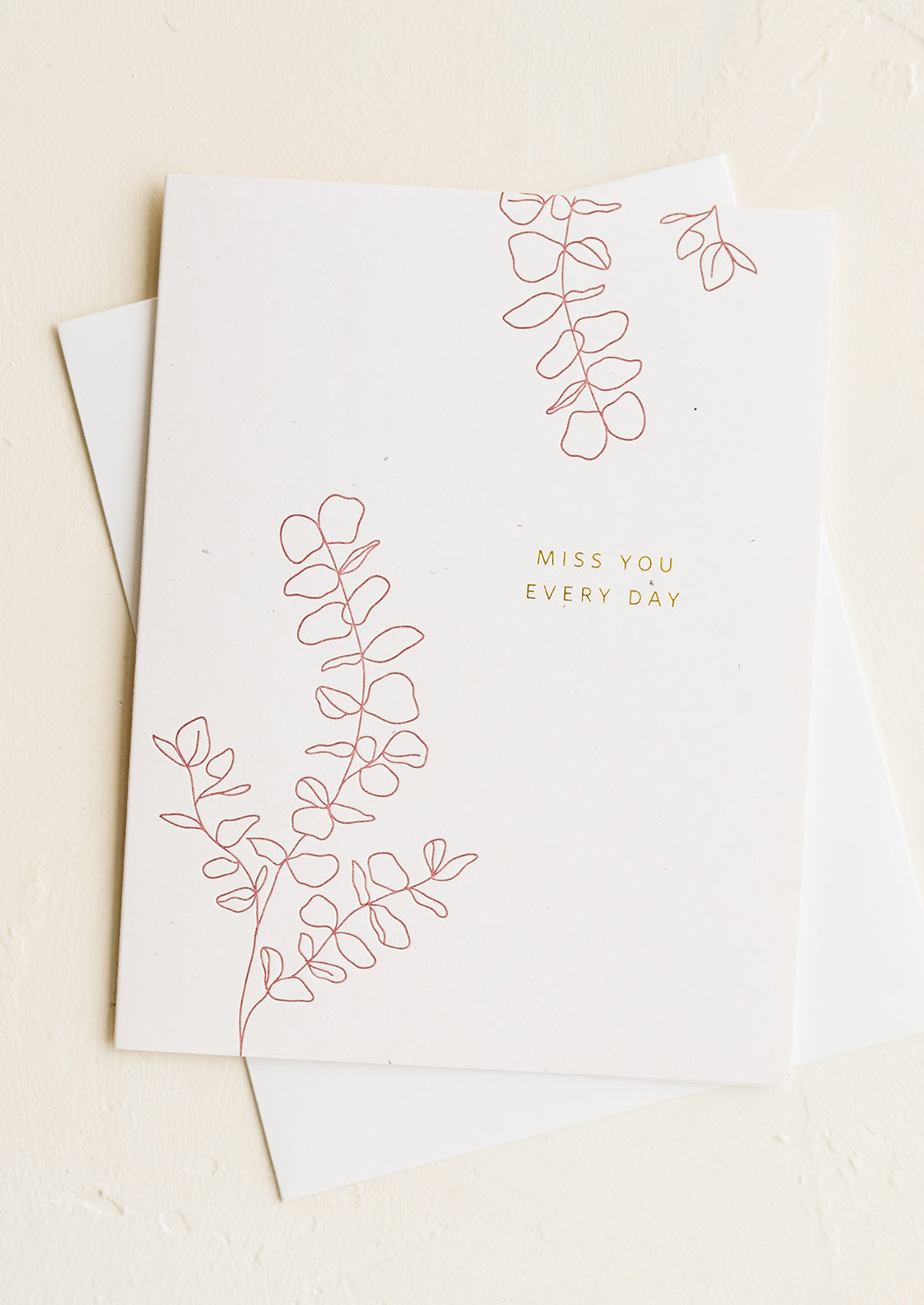 A greeting card with gold lettering reading "Miss You Every Day"