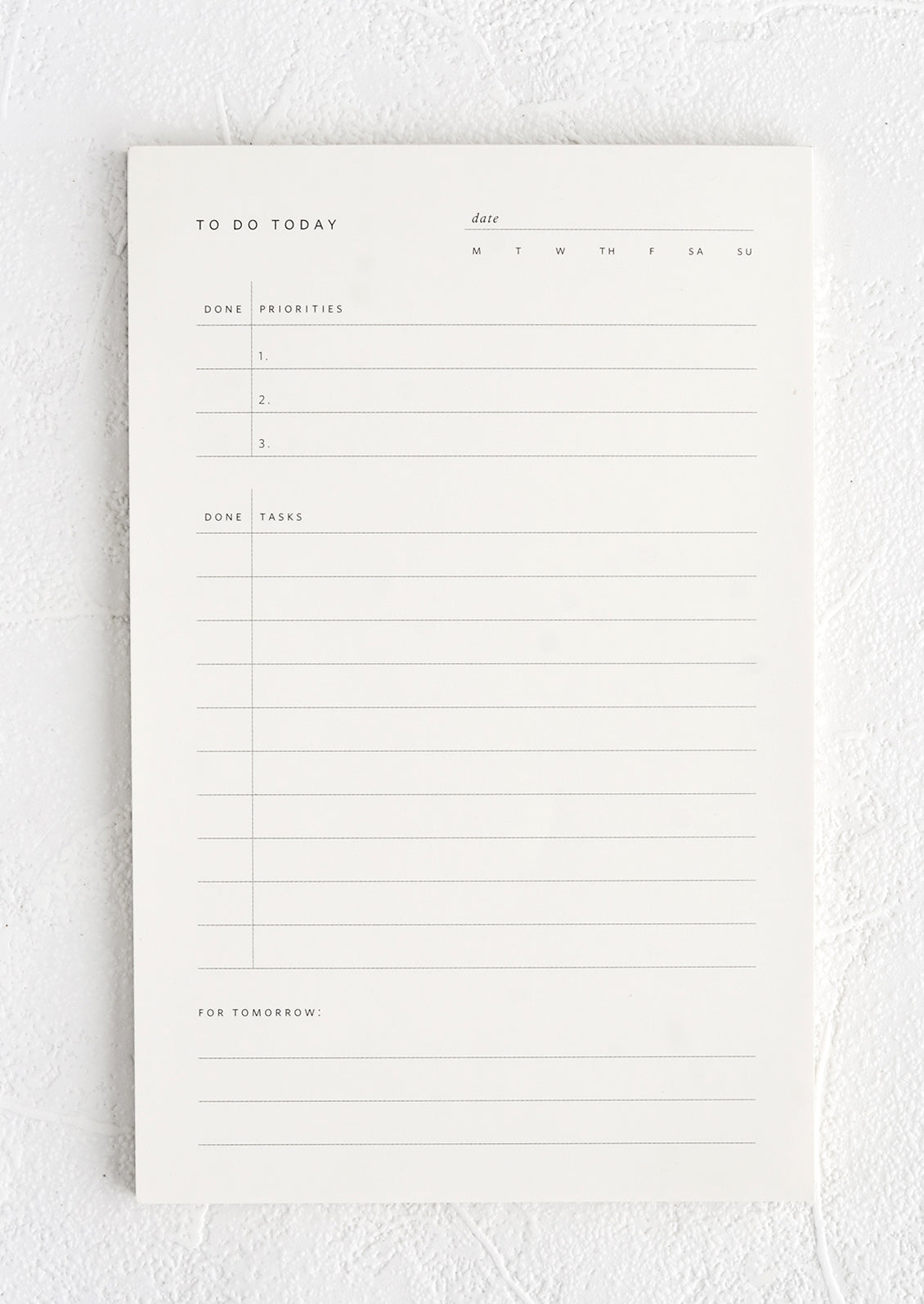 A white notepad with guided prompts for listing daily tasks and priorities.