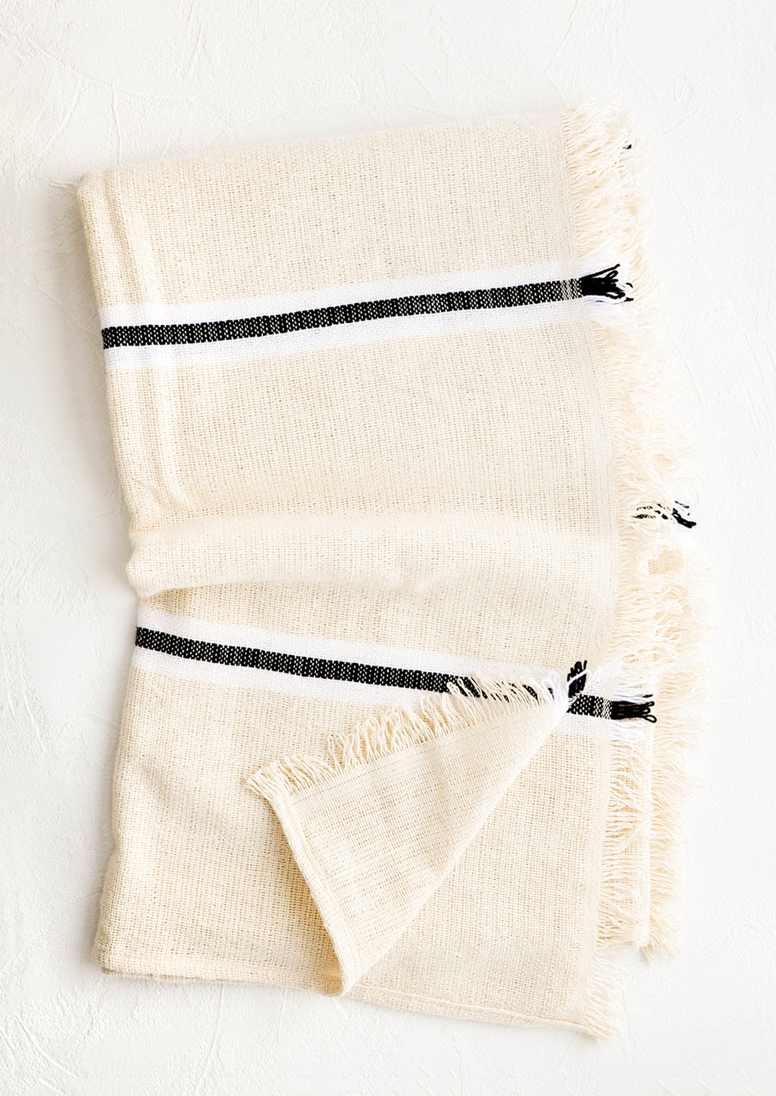 Raw cotton blanket in natural color with black and white stripes and fringed edge