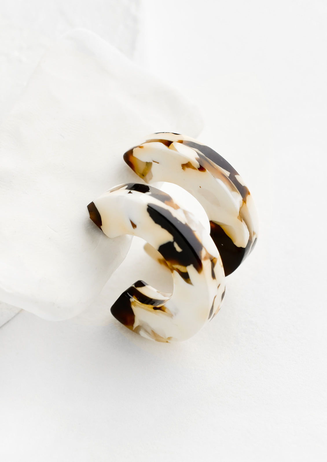 A pair of acetate hoop earrings in brown and ivory.