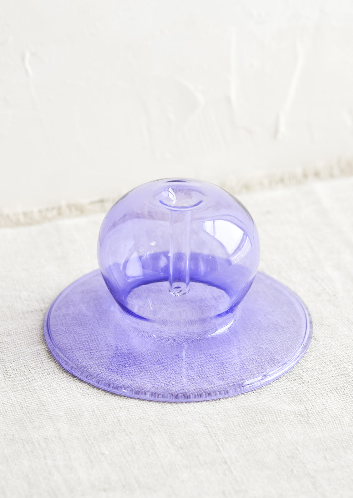 A purple bubble shaped glass form designed to hold stick incense.