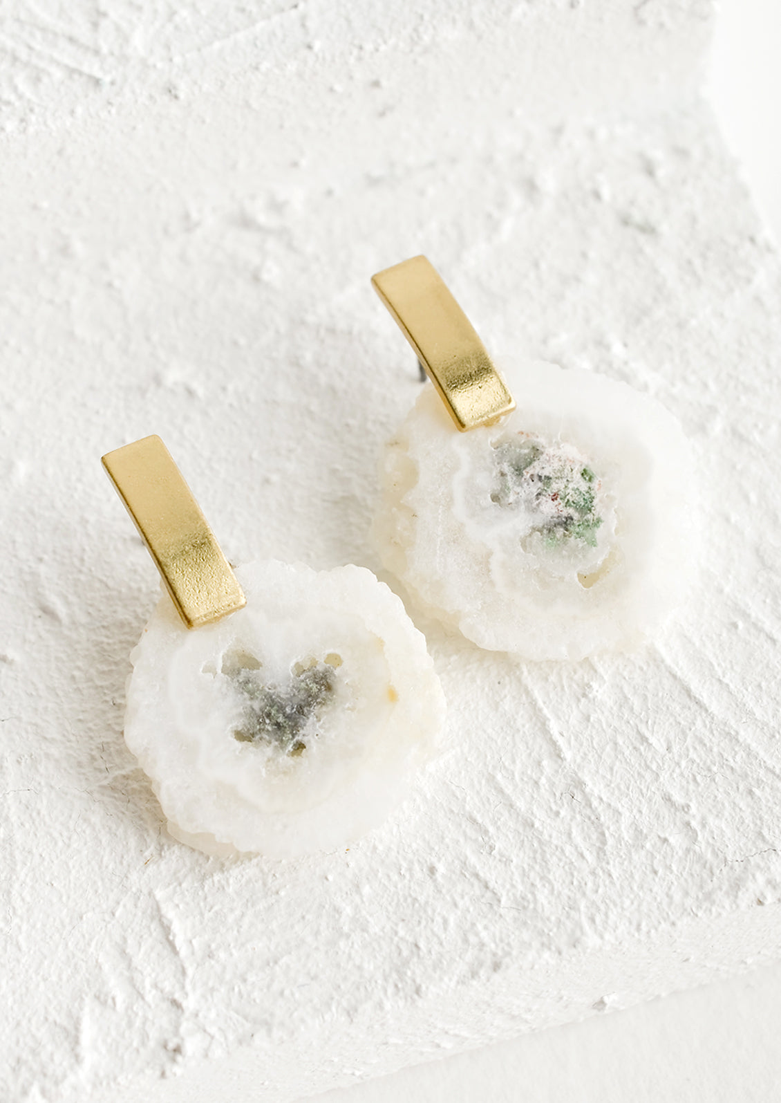 Pair of earrings with raw white quartz gemstone slice and rectangular brass posts.