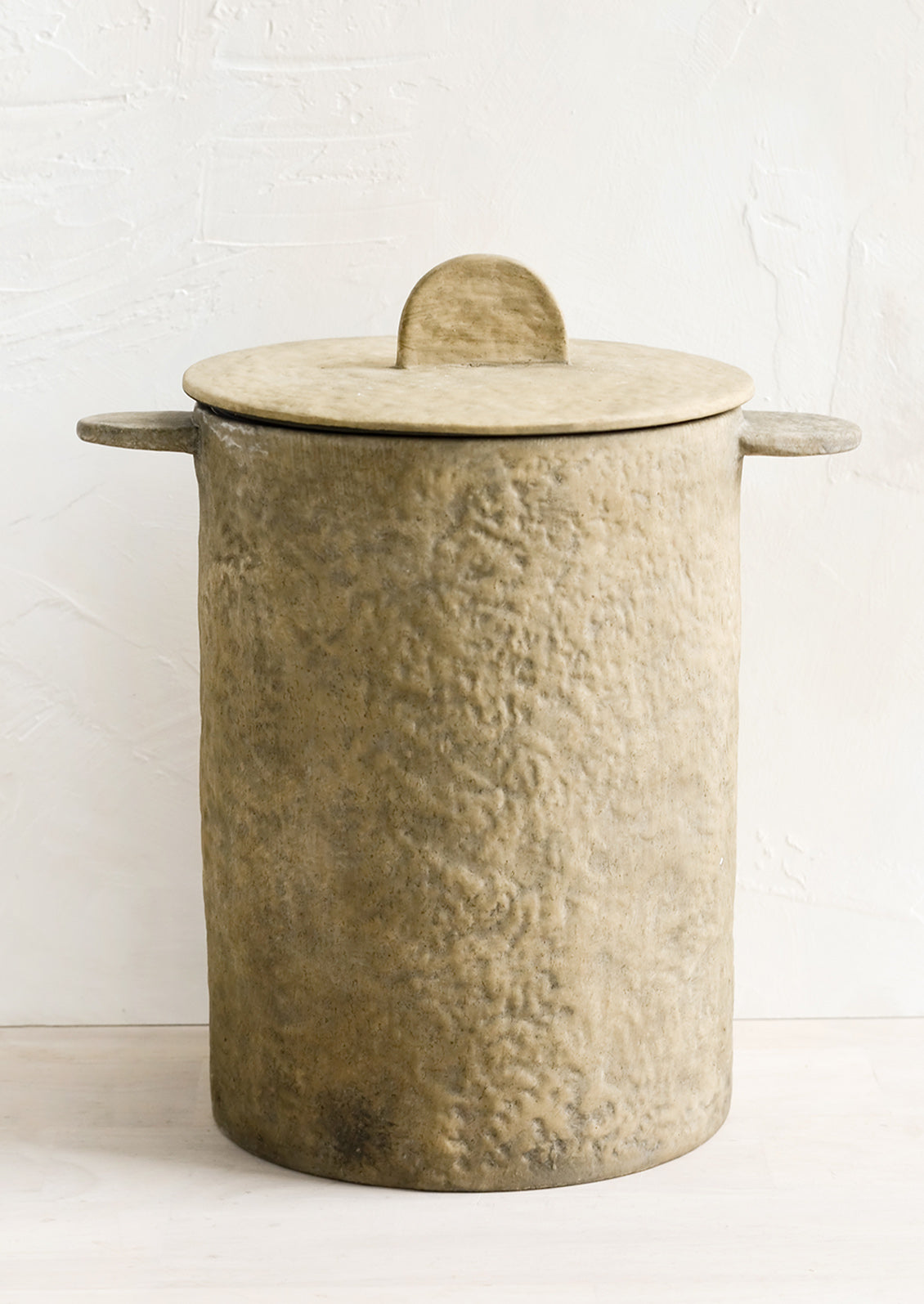 A texture brown clay storage jar with tab-like side handles and detail on lid.