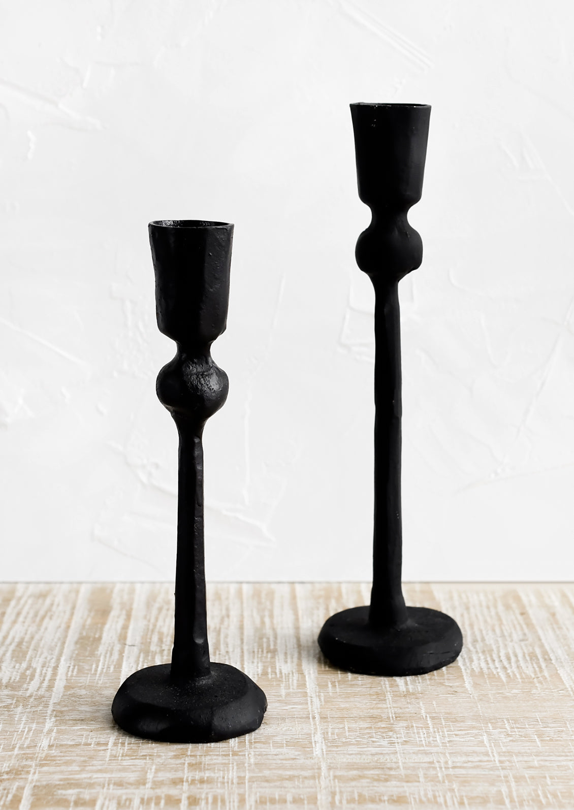 Black cast iron candle holders in spindly, carved silhouette.