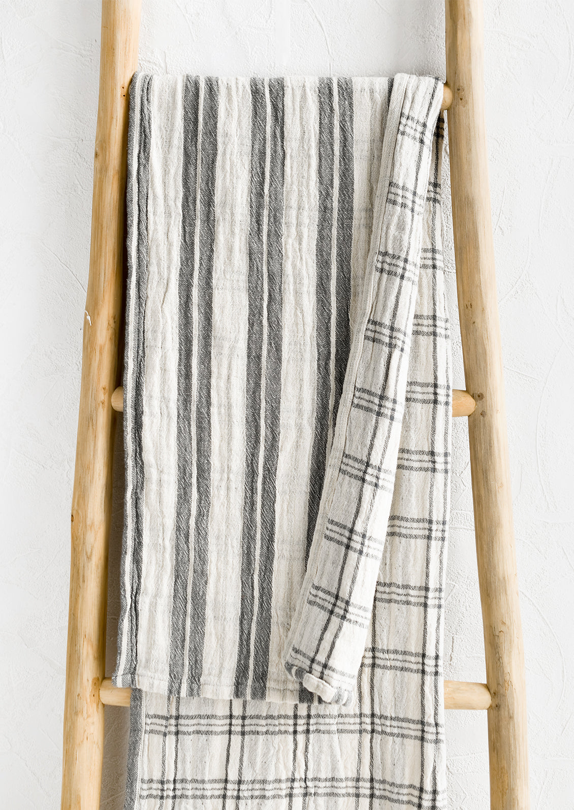 A gauzy table runner with stripes on front and check on back.