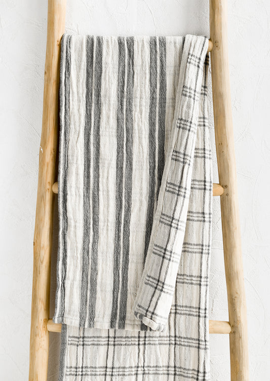 A gauzy table runner with stripes on front and check on back.