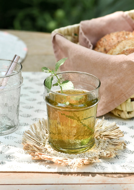 A table setting with short glass tumbler holding mint tea.