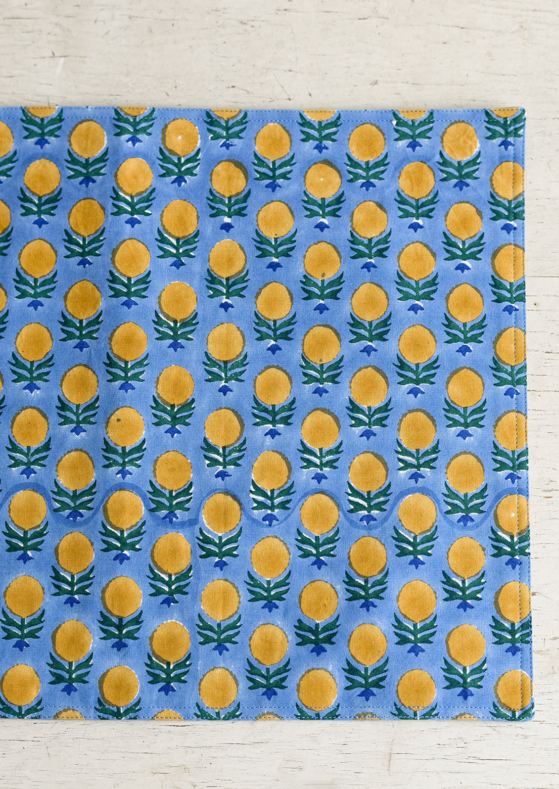 A blue and yellow floral block print placemat.