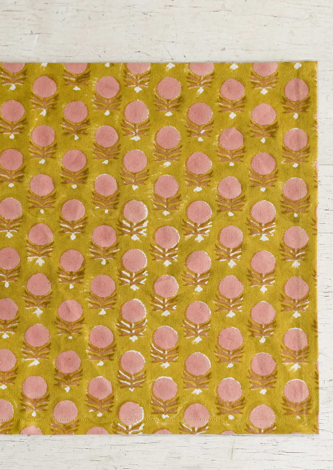 A pink and yellow floral block print placemat.