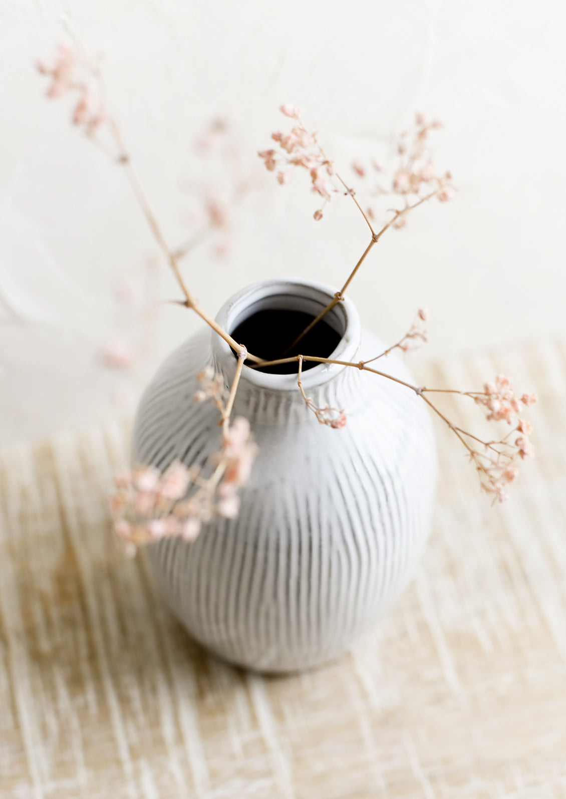 A curvy ceramic vase in white with brown etched stripes.