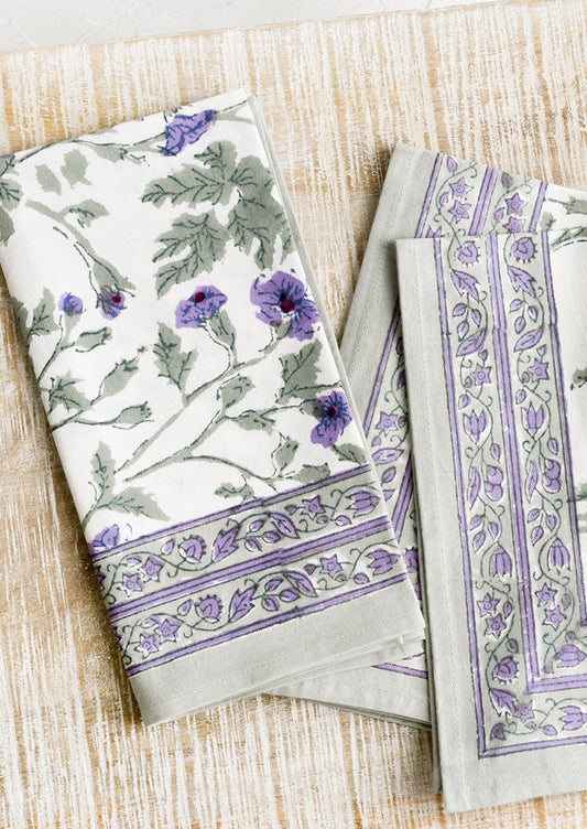 A pair of block printed cotton napkins in green and purple floral print.