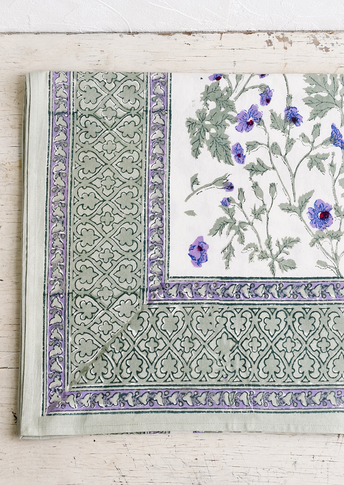 A block printed floral tablecloth in purple and green floral.