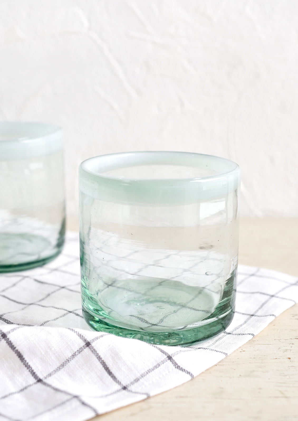 A heavy rocks glass in natural glass with opaque white rim around top.