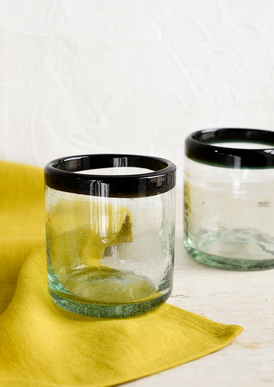 A heavy rocks glass in natural glass with opaque black rim around top.
