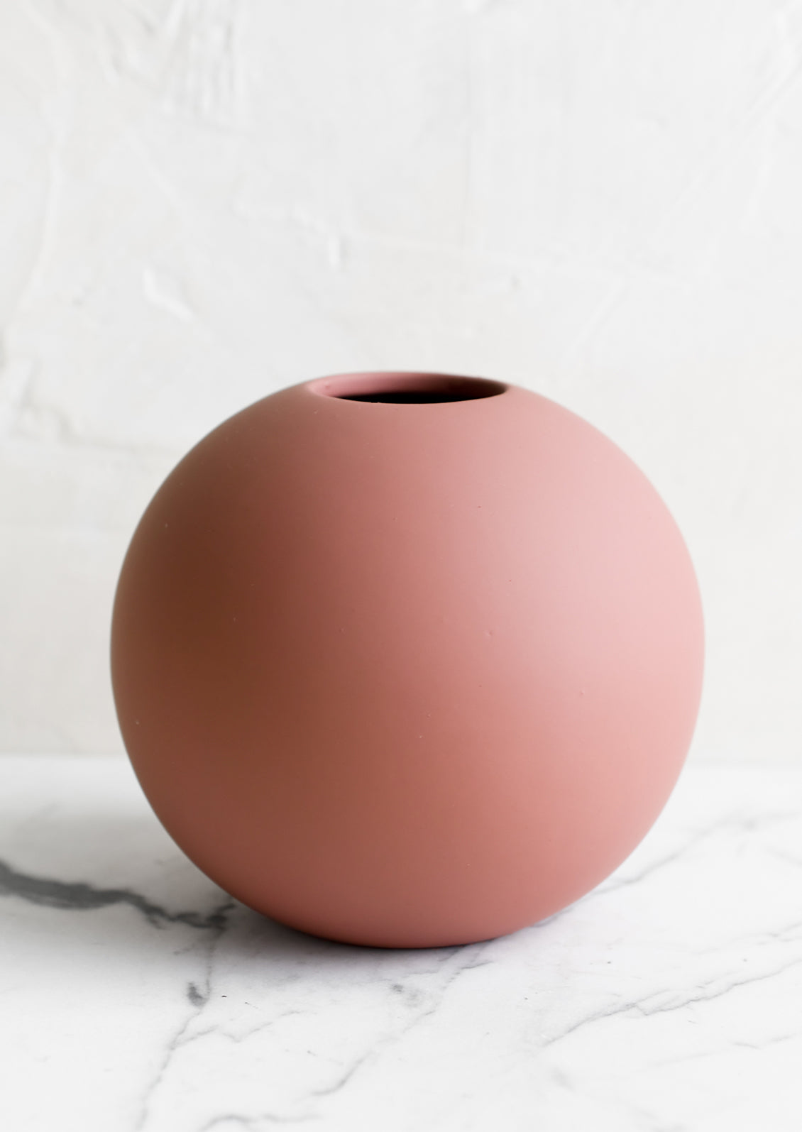 A round matte orb-shaped vase in dusty rose color.