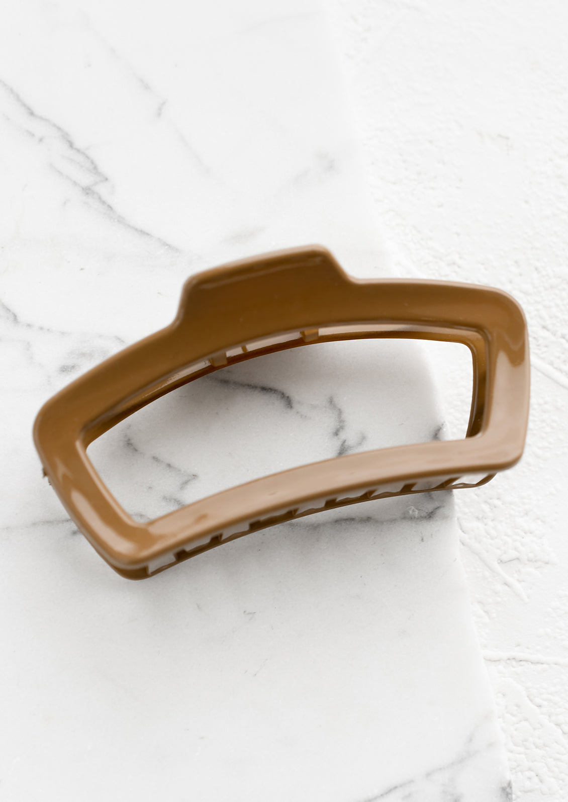 A rounded rectangle hair claw in coffee.