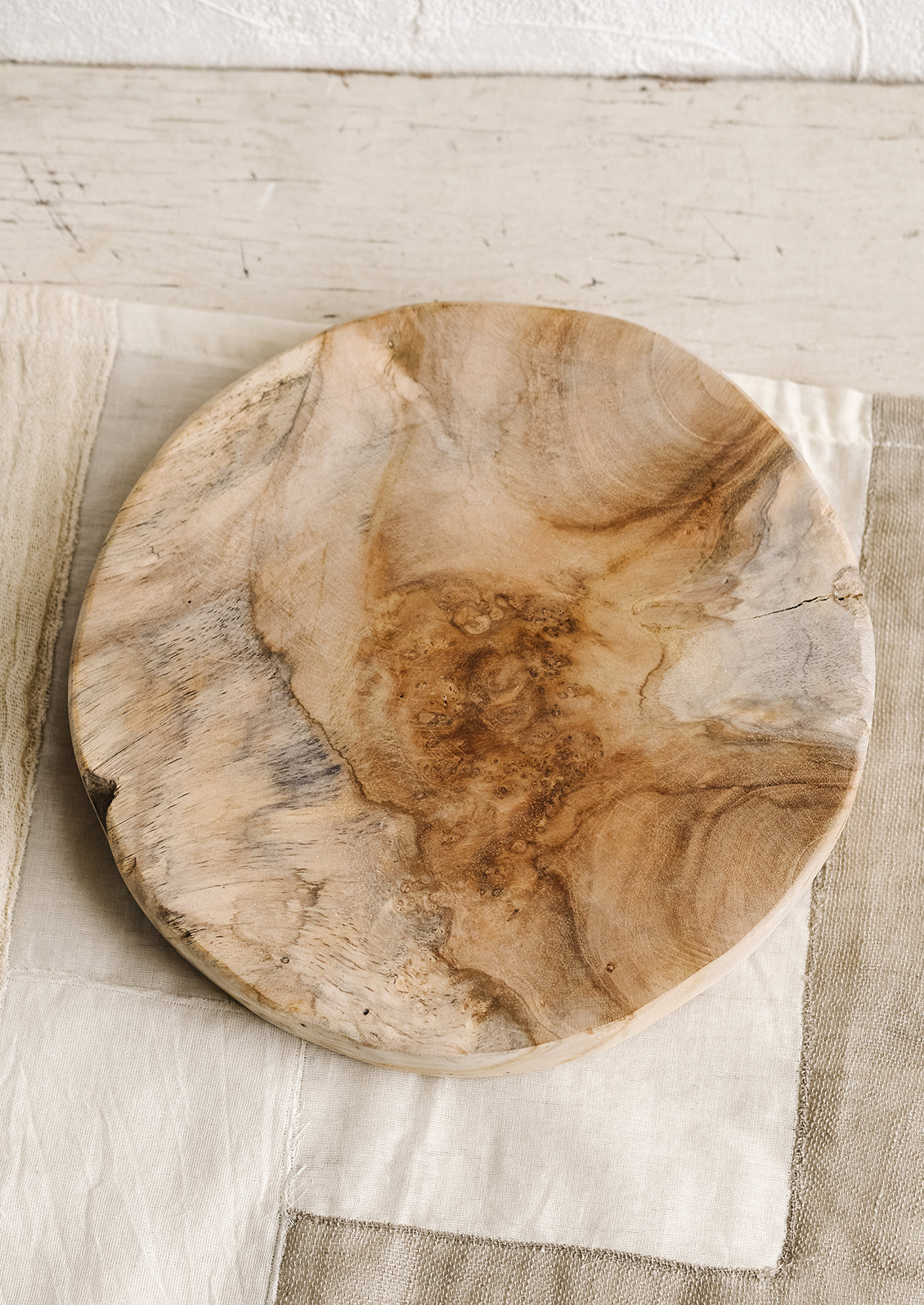 A round pedestal board made from natural teak.