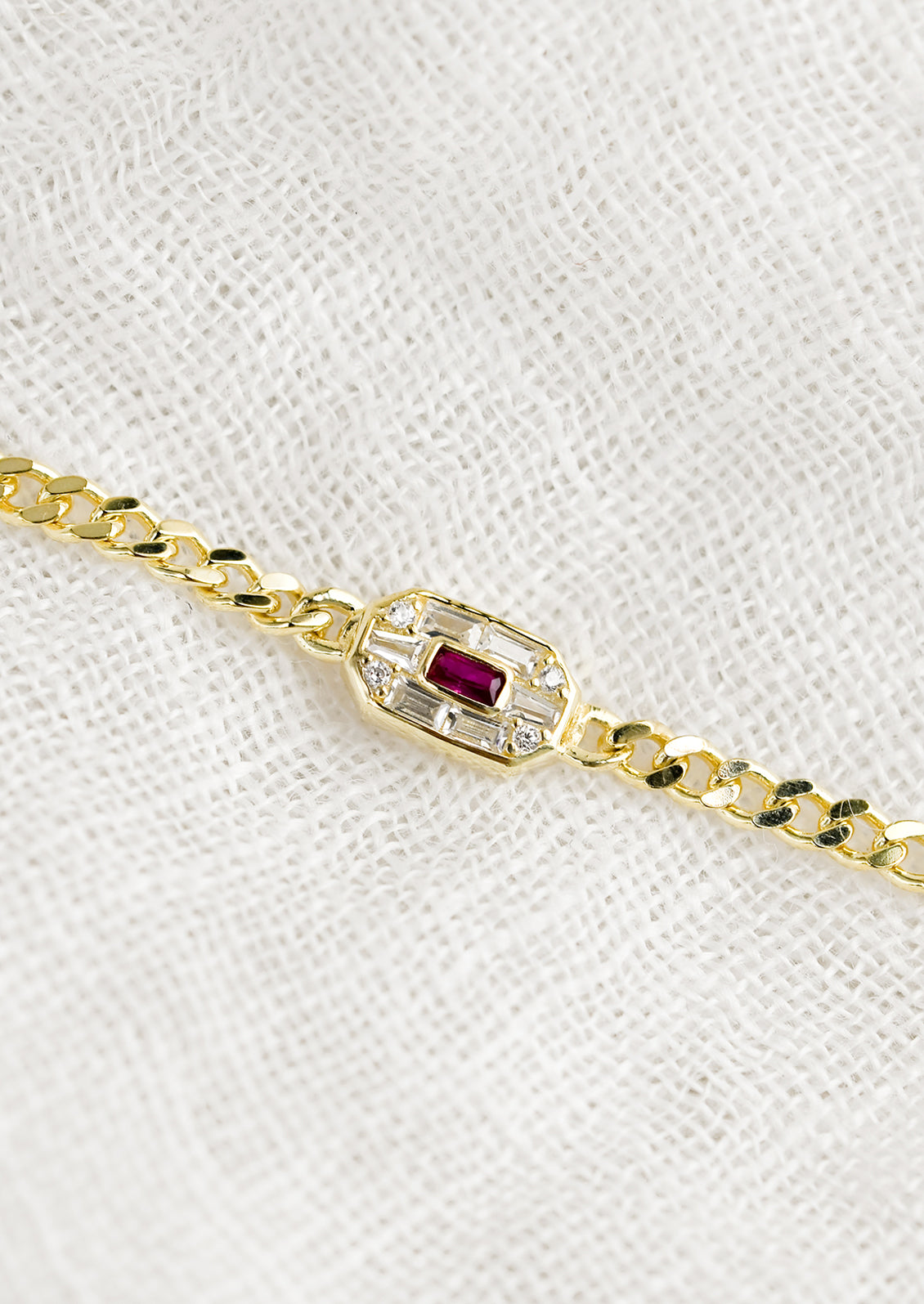 A gold chainlink bracelet with baguette ruby and crystal charm.
