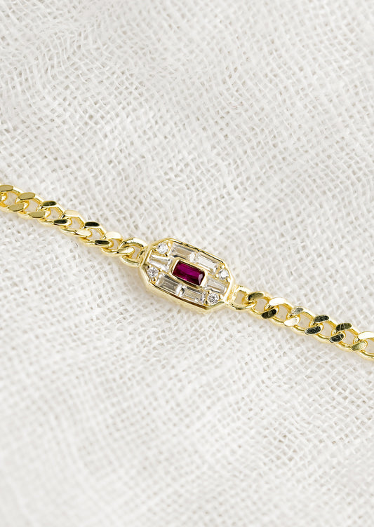 A gold chainlink bracelet with baguette ruby and crystal charm.
