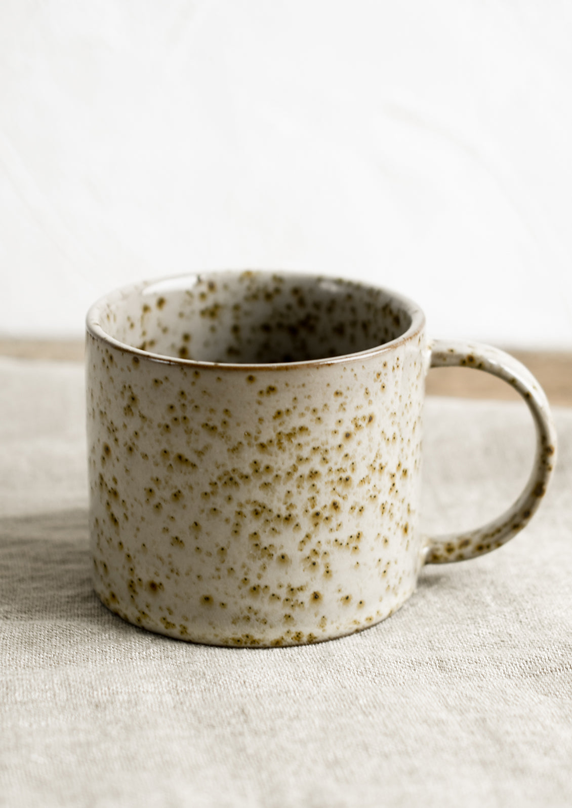 A brown speckled coffee mug with round handle.