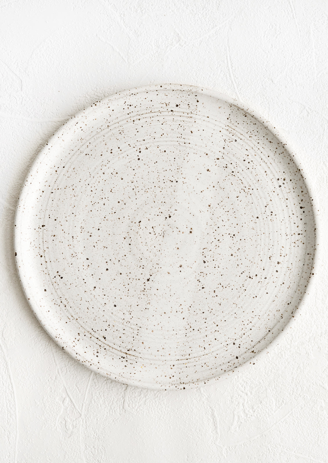 A speckled white ceramic dinner plate.