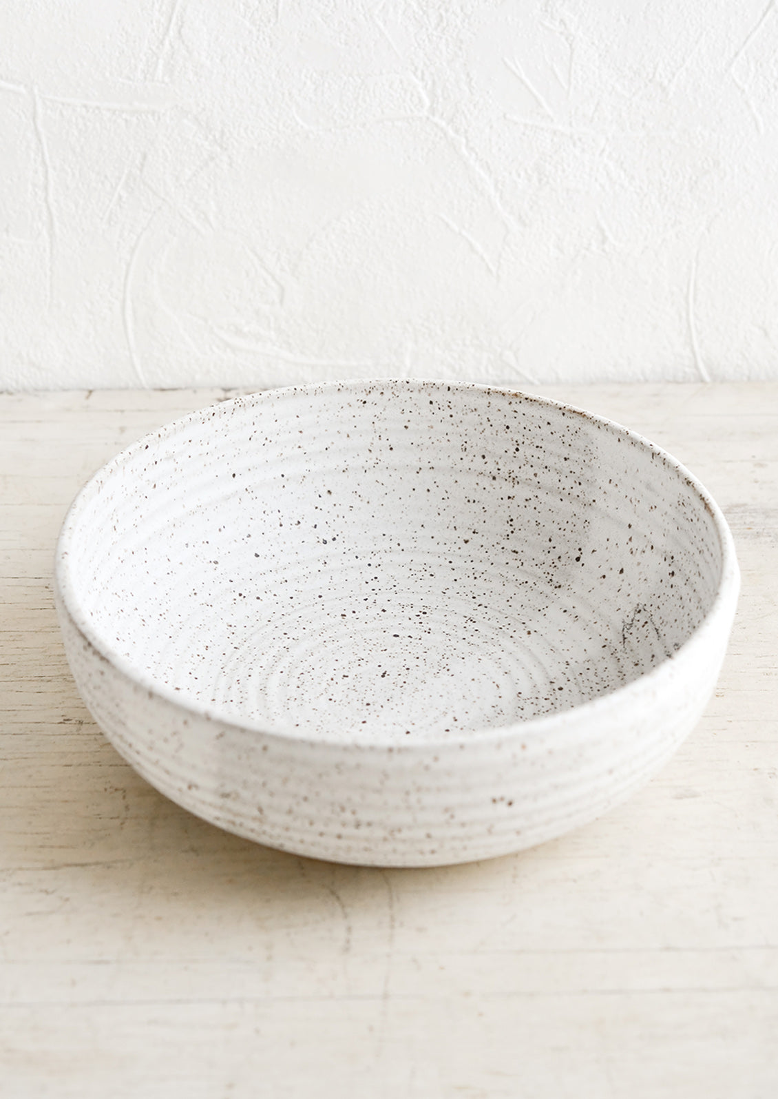 A ceramic serving bowl in matte speckled white.