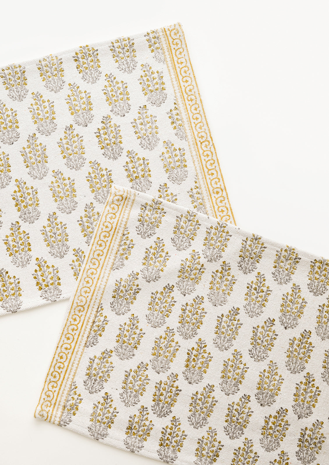 Two ivory rectangular cotton placemats with yellow floral pattern.
