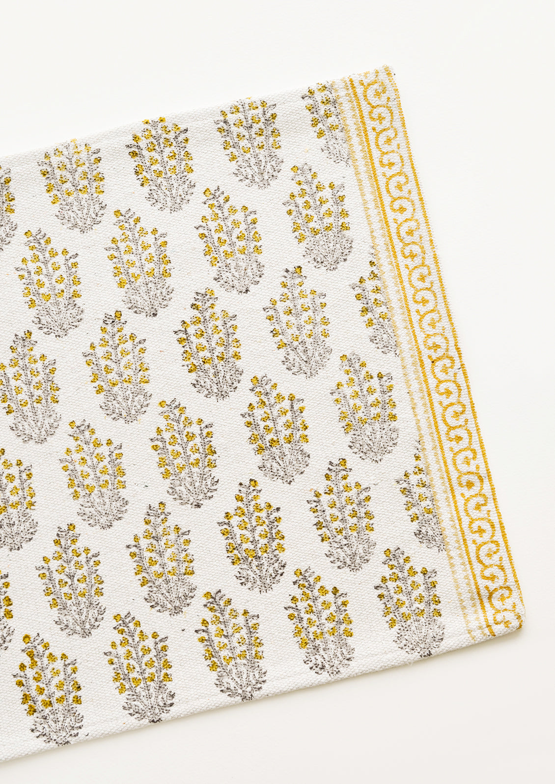 An ivory rectangular cotton placemat with yellow floral pattern.