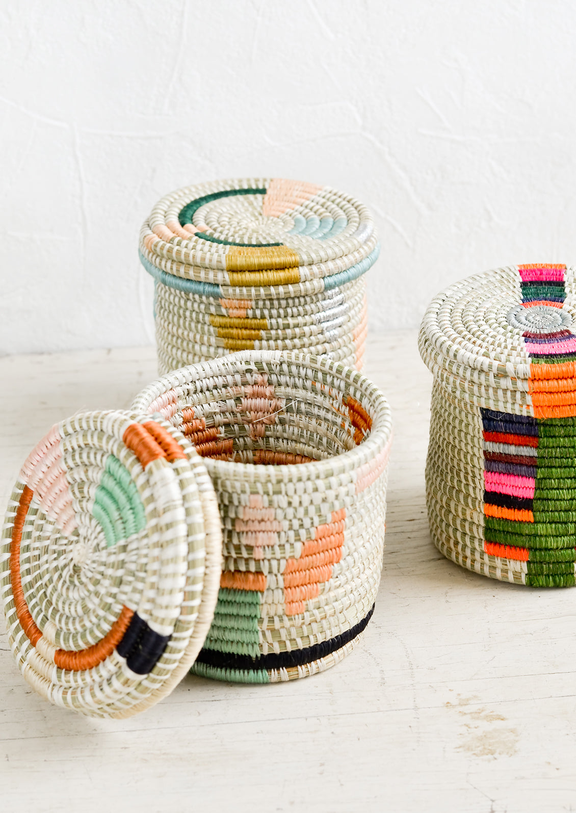 Assorted lidded woven baskets in a mix of colors and patterns.