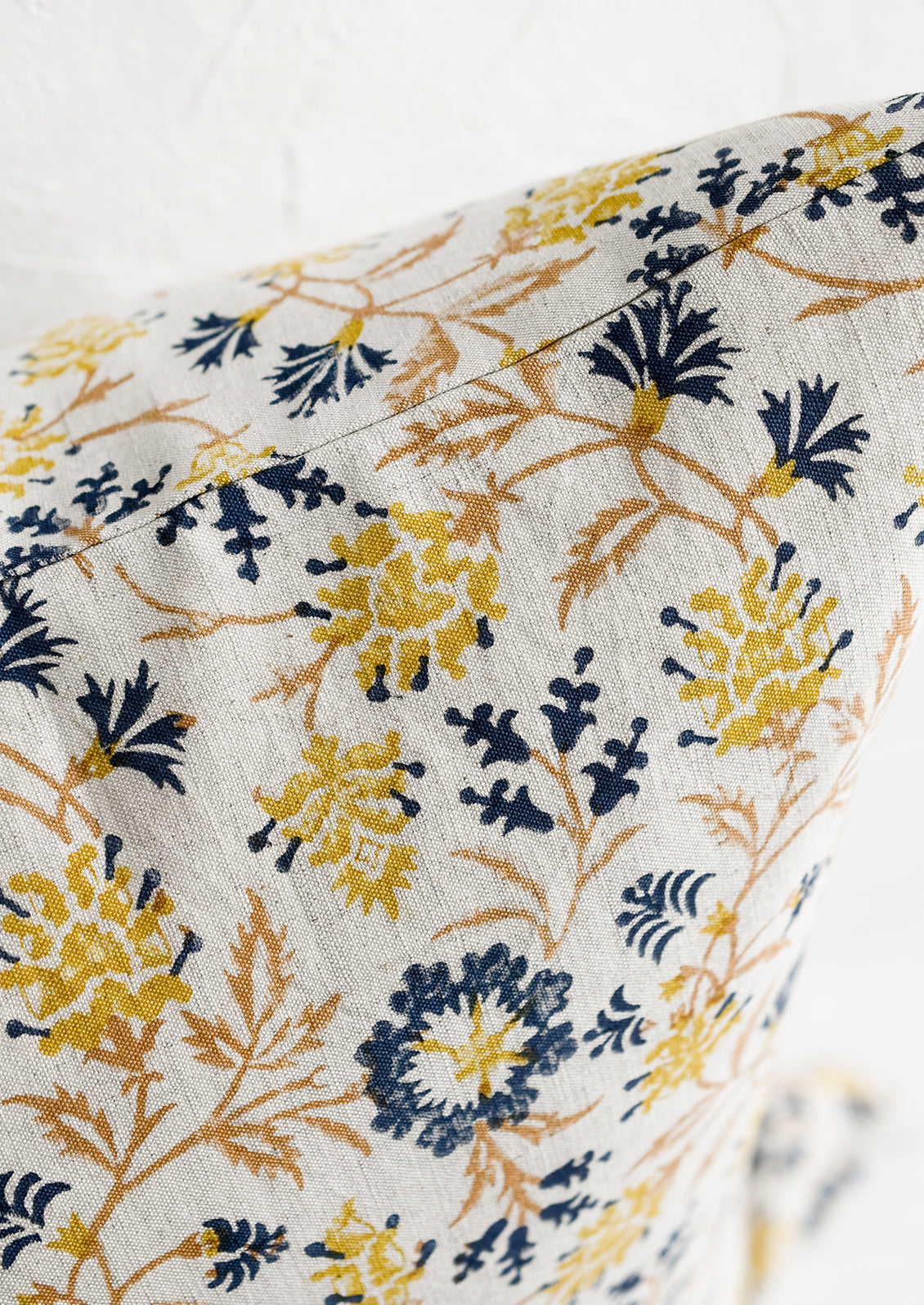 A block printed pillow in navy, brown and yellow floral print on natural linen.