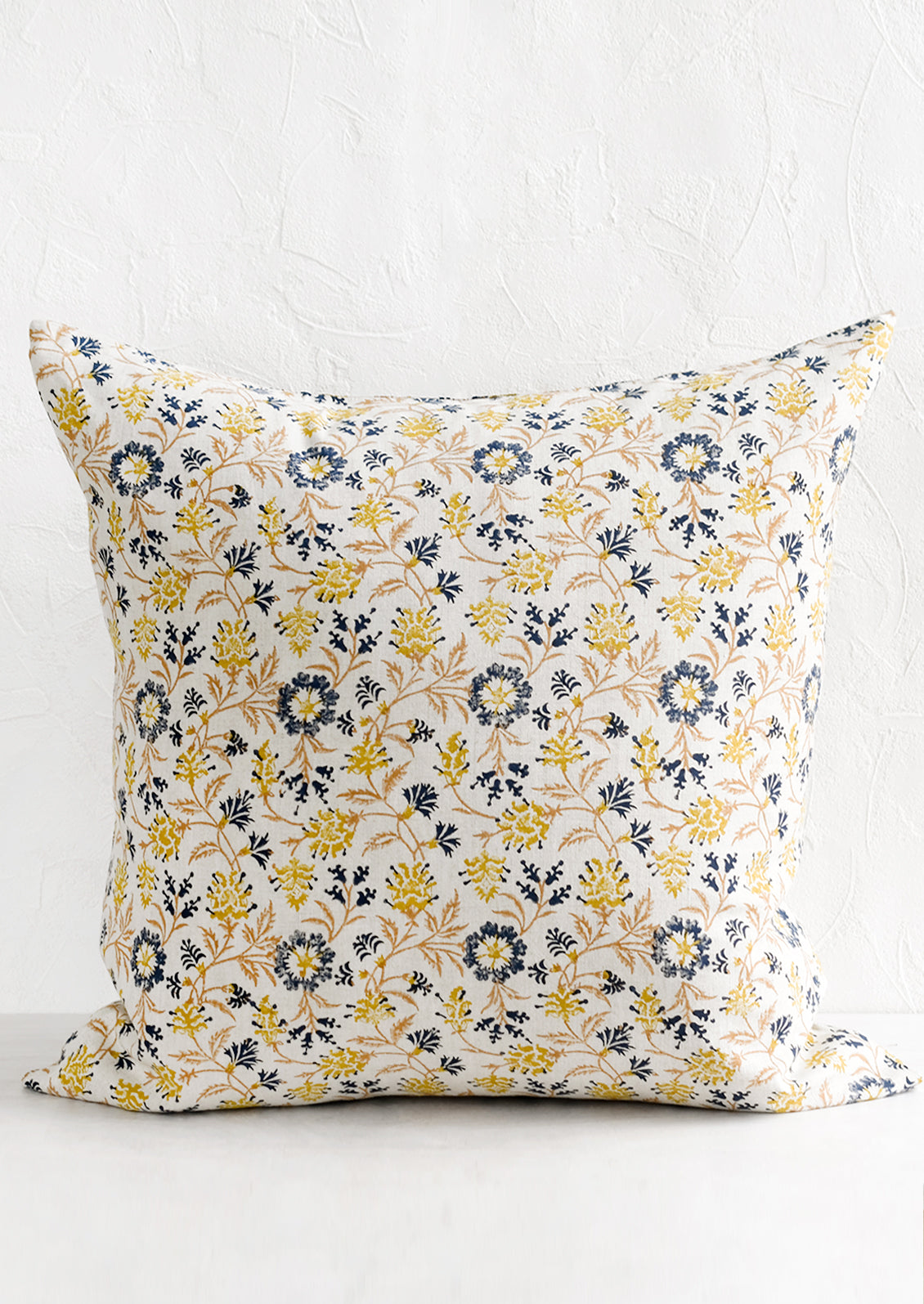 A block printed pillow in navy, brown and yellow floral print on natural linen.